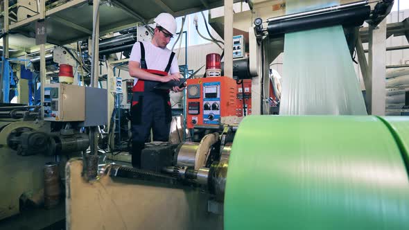 Factory Machine Is Producing Polyethylene Foil Under Worker's Control