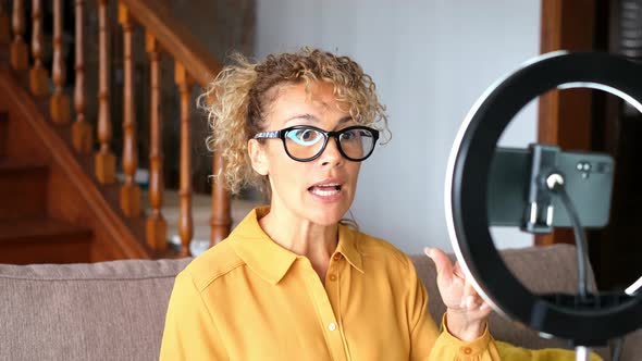 Portrait of beautiful adult woman speaking in front of a phone to record online content