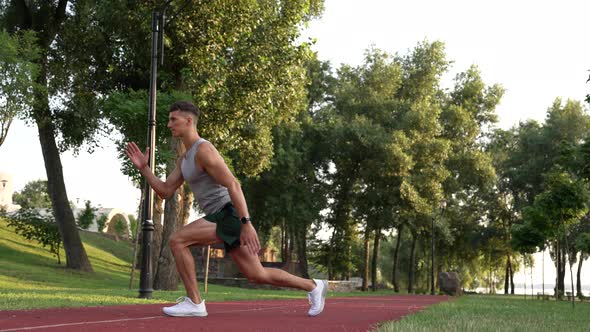 Muscular Man Warming Up with Back Lunge Exercise Outdoor Training