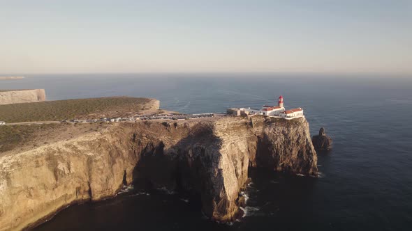 Aerial shot of Cape Saint Vincent lighthouse on eroded high cliff surrounded by Atlantic Ocean.