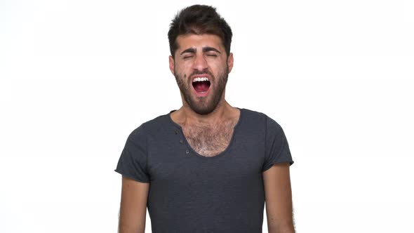 Picture of Handsome Young Man in Grey Tshirt Looking at Camera Yawning Covering Mouth with Fist