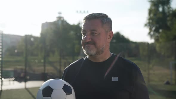 Bearded Mature Caucasian Sportsman Posing with Soccer Ball Outdoors in Sunbeam