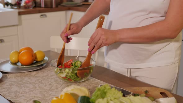 A Happy Pregnant Woman Preparing a Vegetable Salad and Dancing in a Kitchen