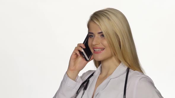 Female Doctor Talking on Mobile Phone. White. Closeup