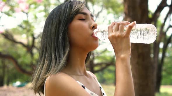 Young Brunette Woman Drinking Water in the Park