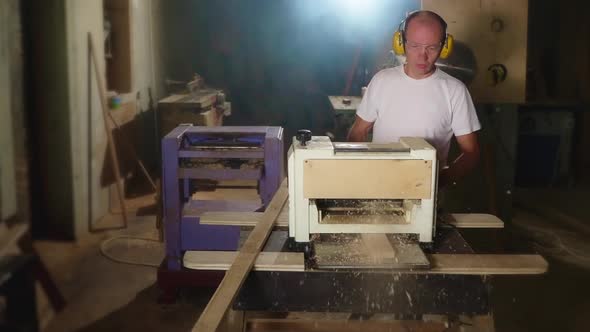 Working Studio of Skilled Carpenter Woodworker is Processing Board By Grinding Machine