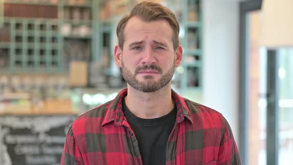 Portrait of Upset Young Man Crying at Camera