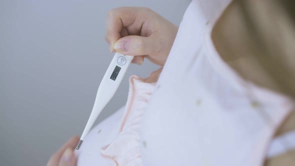 Pregnant Lady Looks at Modern Thermometer with Data Closeup
