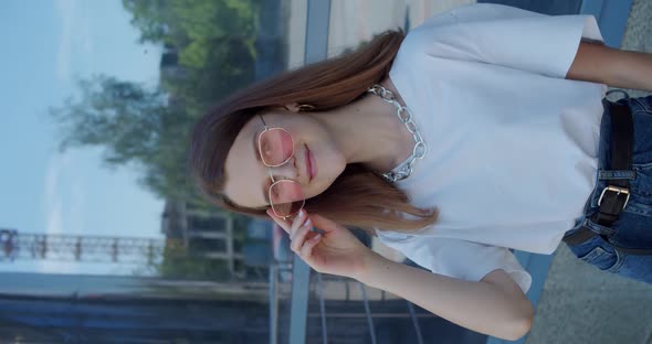 Portrait of Happy Young Girl Smiling at Camera and Correcting Stylish Sunglasses