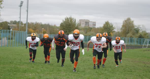 American Football Training Day, Athletic Football Players in Protective Gear Run Along the Playing