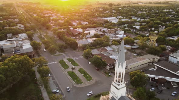 Aerial parallax of a church bell tower and revealing a small town at golden hour