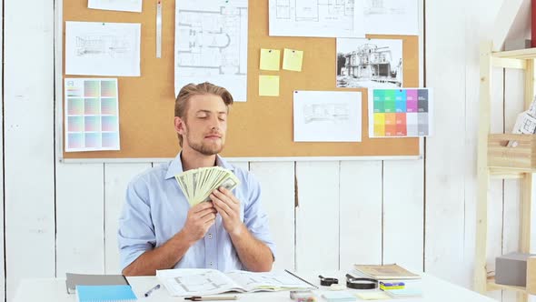 Successful Architector Holding Sniffing Money Sitting at Workplace Slow Motion