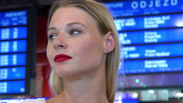 A Young Beautiful Woman Looks Around in a Train Station Building - a Board with Departures