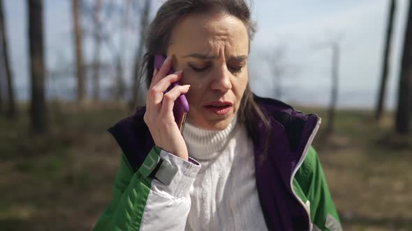 Stressed Anxious Woman Talking on Phone Standing in Forest Alone