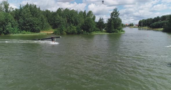 Wakeboarding in a Lake Near the Forest, Sportsman Surfs on the Water, Ride on a Wakeboarding Board