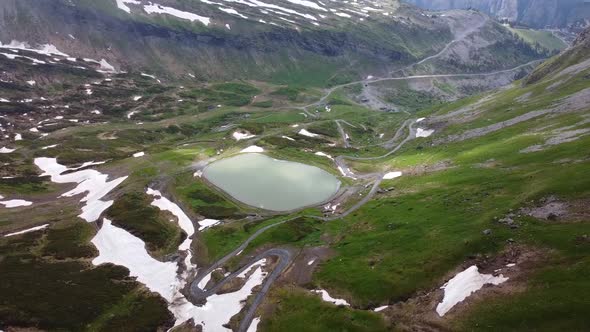 Drone shot (rotating) of a Ski Resort in the Summer with a Water Reserve and Patches of Snow