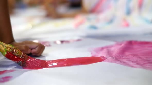 Close up on paintbrush with wet red paint being brushed onto large white sheet of paper filmed in sl