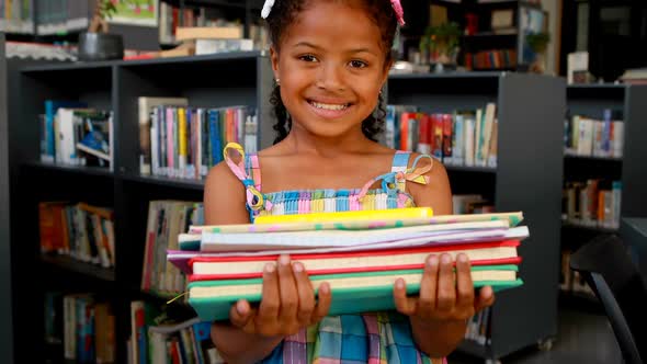 Portrait of happy schoolgirl standing with book stack 4k