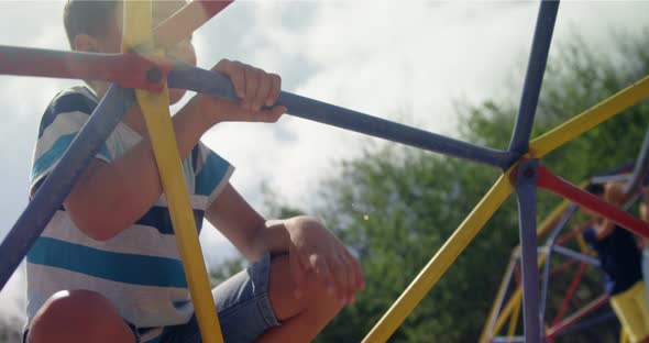 Schoolboy climbing on dome climber in playground