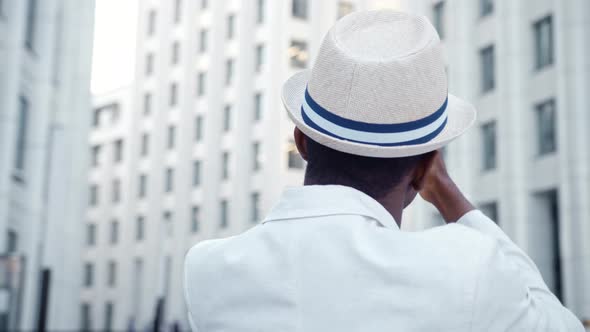 Black man tourist in suit films panorama of local highrise office buildings