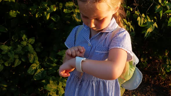 Kid using smartwatch outdoor in park. Child talking on vdeo call on the smartphone browsing internet