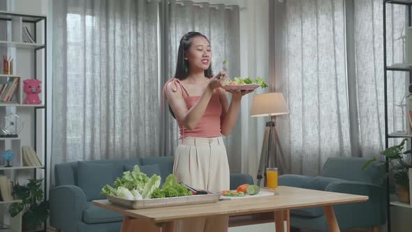 Asian Woman Eating Healthy Food Before Smiling And Showing Thumbs Up Gesture To Camera At Home