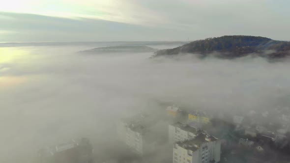 Aerial Survey of Mountains Covered with Thick Morning Fog. Fairy Fog Lies in the Valley Between the