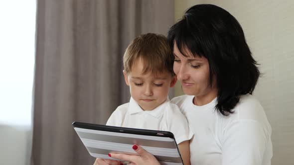 Mom and Her Child Spend Time at the Tablet at Home, Playing and Watching Cartoons, Playing Video