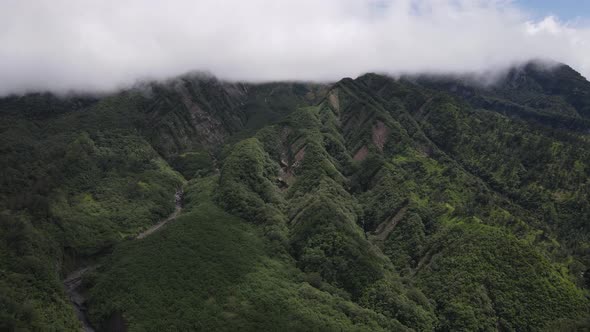 Aerial view of flying in a tropical forest, mountain, and valley in Indonesia.