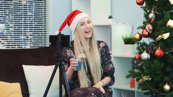 Gorgeous Woman in Santa Hat Recording Video Vlog By Smartphone on Tripod