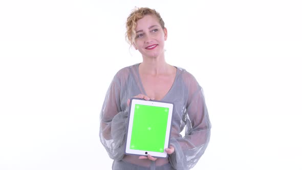 Happy Beautiful Blonde Woman Thinking While Showing Digital Tablet