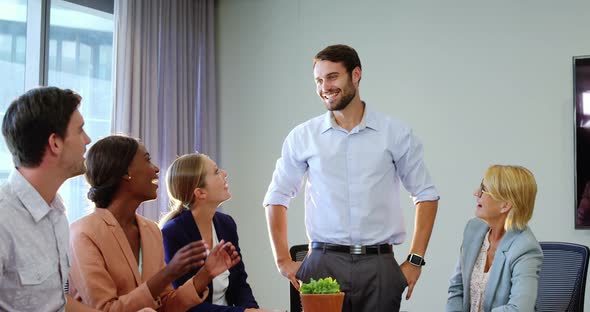 Businesspeople interacting and applauding a coworker