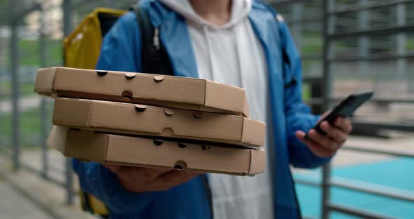 Crop View of Delivery Person with Transportation Bag Looking at Map on Smartphone While Walking Near