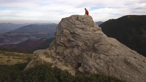 Aerial view of a hiker man climbing big rock in mountains