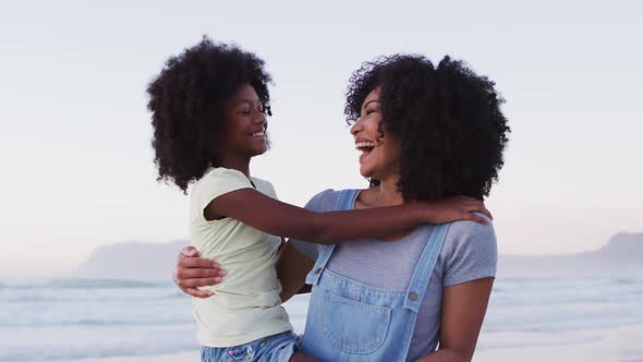 Portrait of african american mother and daughter smiling together at the beach