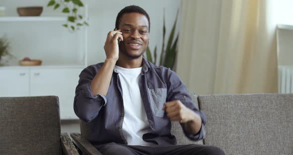 Afro Student Learns Good News on Phone Enjoys Sitting at Home. Black Male Businessman Freelancer