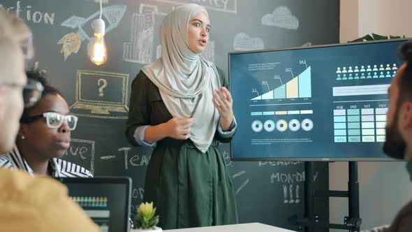 Muslim Businesswoman in Hijab Talking to Group of Colleagues During Presentation in Office