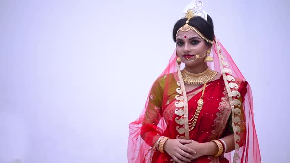 Isolated Indian Bengali bride wearing red saree smiles against white background