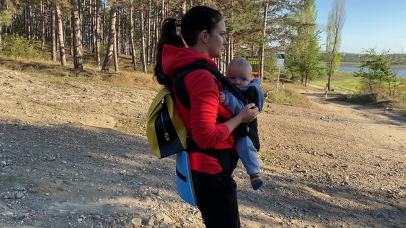 Happy Mother with Her Smiling Baby in Infant Kid Carrier on a Walk Mom with Baby Boy in Hipseat