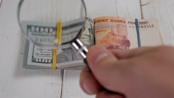 Closeup of Hundreddollar Bills and Five Thousand Rubles in a Magnifying Glass