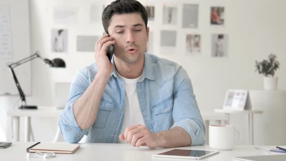 Casual Young Man Talking on Phone at Work