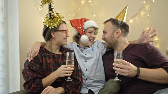 Friendly Family of Three Is Celebrating New Year or Christmas. Parents Are Drinking Champagne.