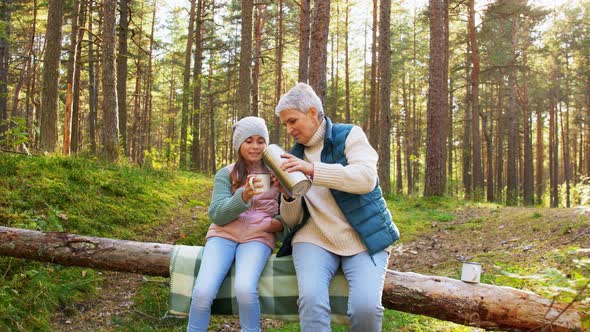 Grandma with Granddaughter Drinking Tea in Forest