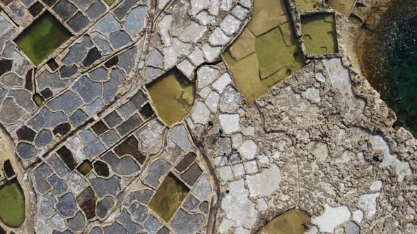 People walk among the ancient Salt Pans on the island of Gozo in Malta as seen from above.