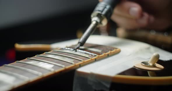 Guitar Tech Heats Frets on Guitar By Soldering Iron Before Refretting Guitar Artisan's Preparations