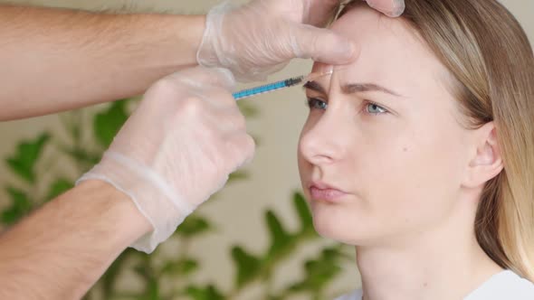 Close Up of Hands of Expert Beautician Injecting Botox in Female Forehead