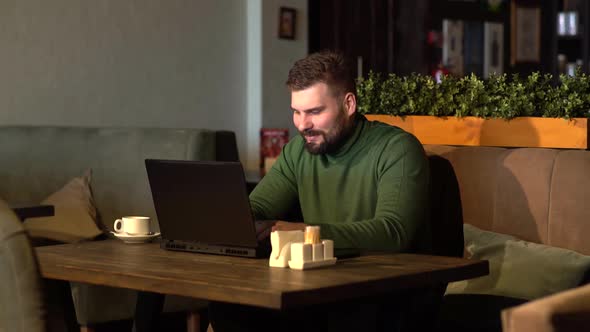 Business Man Using Laptop, Drinking Coffee and Smiling While Working in Cafe