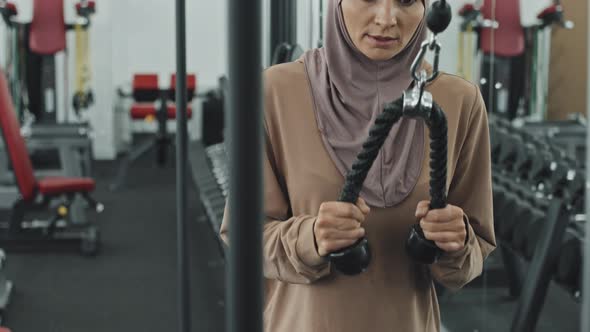 Muslim Woman Doing Standing Pulldowns with Cable Machine