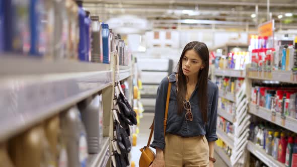 Woman Customer Choosing Motor Oil From Wide Assortment Represented in Department with Car Goods