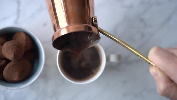 Woman pouring coffee from turk into cup